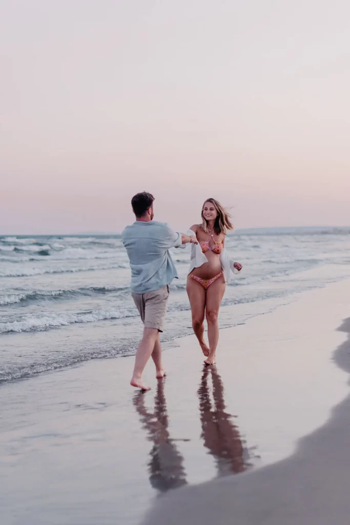 Femme enceinte avec son conjoint posant à la plage pour immortaliser sa grossesse.